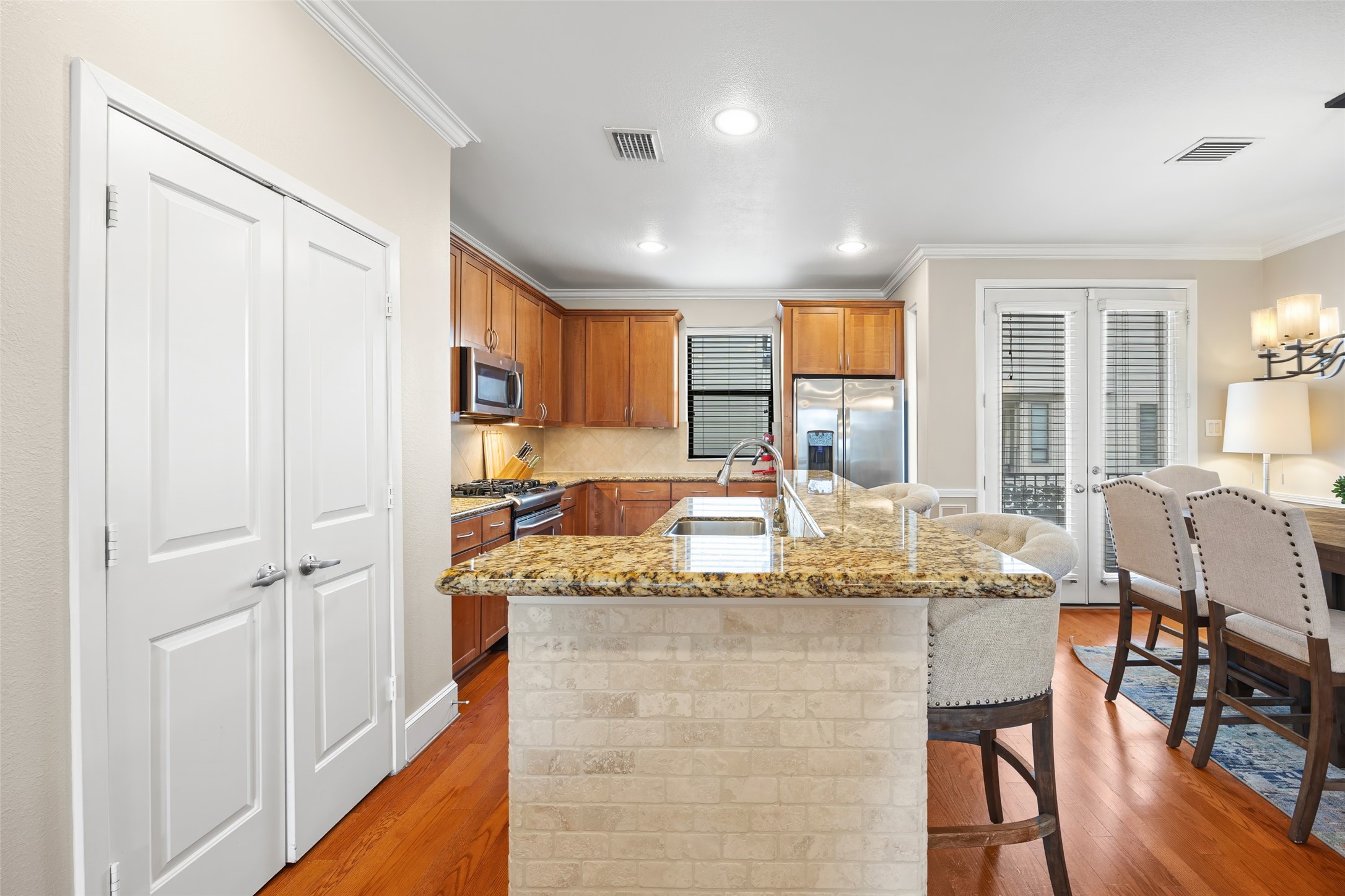2320 Emancipation Avenue Houston, TX 77004 - Photo 19 of 38 a dining hall with stainless steel appliances granite countertop furniture a kitchen island a stove a refrigerator with white cabinets and wooden floor