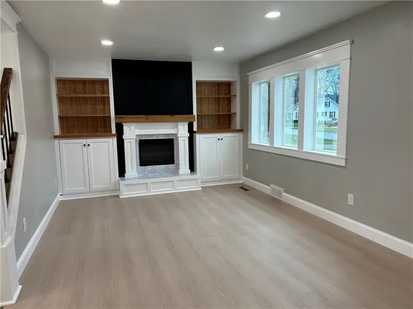 an empty room with windows a fireplace and a flat screen tv