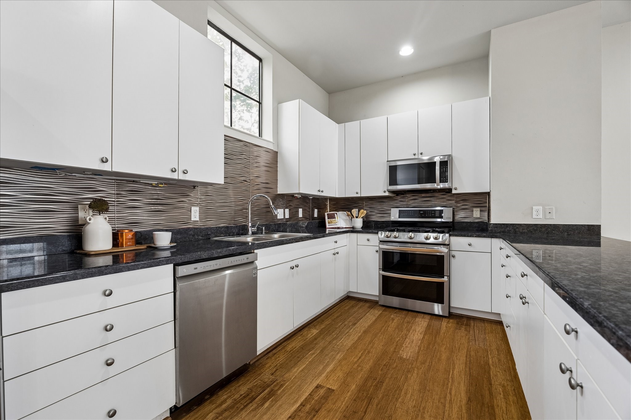 939 Colorado Street, Unit 22 Houston, TX 77007 - Photo 21 of 23 a kitchen with stainless steel appliances granite countertop a stove a sink and white cabinets