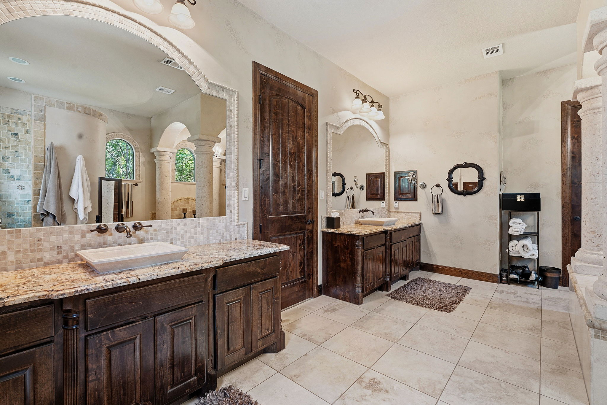 816 Brave Face Street Leander, TX 78641 - Photo 17 of 40 A primary bathroom featuring dual vanities with granite counters and rich wooden cabinetry.