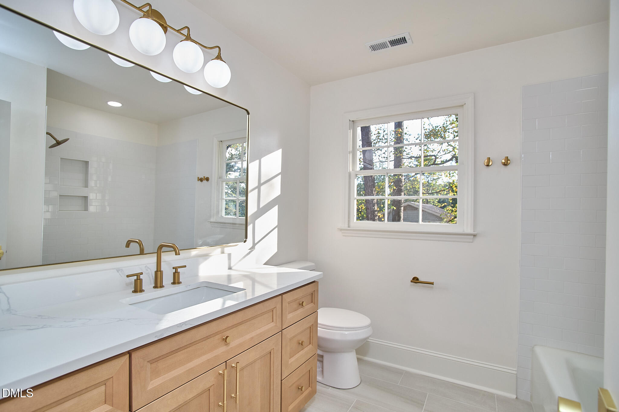 5721 Timber Ridge Drive Raleigh, NC 27609 - Photo 12 of 76 a bathroom with a toilet a sink a mirror a window and vanity