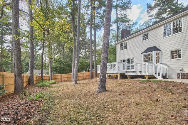 an aerial view of a house with a yard and trees all around