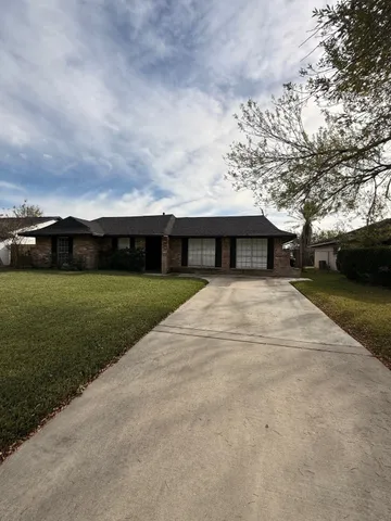 a view of house with yard and car parked