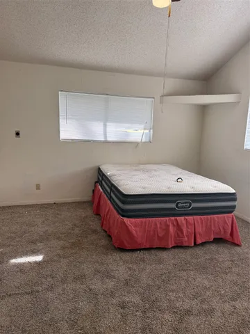 a spacious bedroom with a bed and a night stand