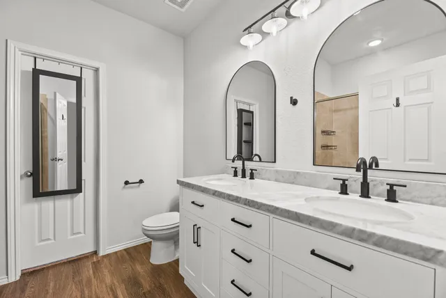 a spacious bathroom with a granite countertop toilet a sink and a mirror