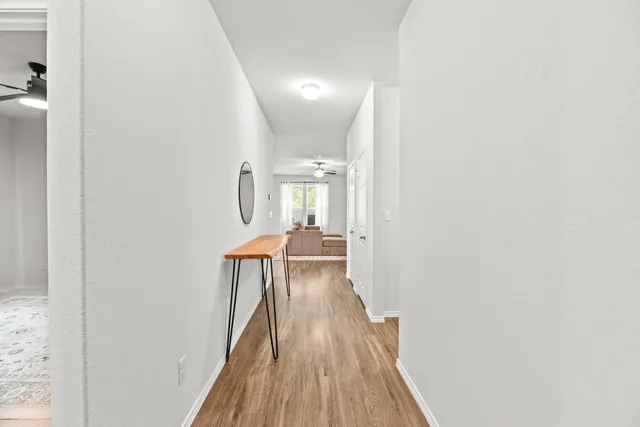a view of a hallway with wooden floor and a living room