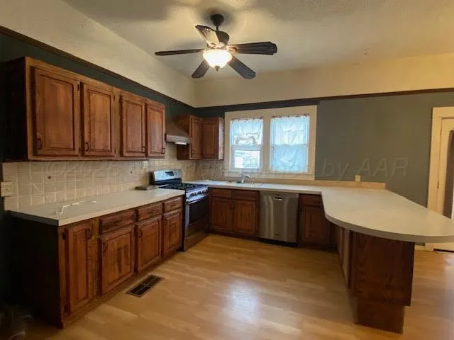 a kitchen with a stove a sink a refrigerator cabinets and a window