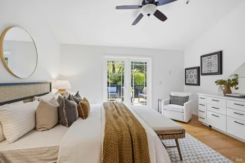 a bedroom with a bed a couches and large windows