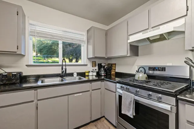 a kitchen with stainless steel appliances granite countertop a sink stove cabinets and a window