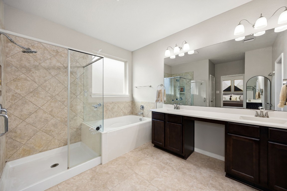 14023 Beaverhead Range Court Conroe, TX 77384 - Photo 15 of 29 Indulge in a spa-like retreat in the expansive primary bathroom. This well-appointed space offers a perfect balance of functionality and relaxation, ensuring a serene start and end to your day. Dual vanities, large mirror, separate tub and shower, frosted window, and elegant finishes complete this spa-like bathroom.