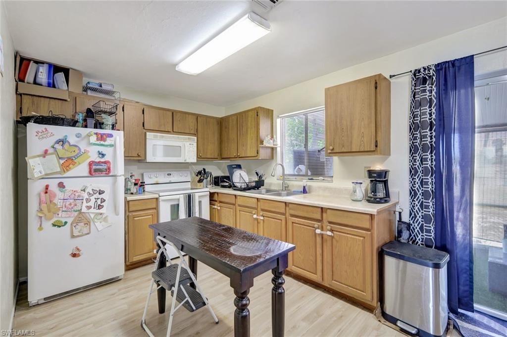 7481-7485 Pebble Beach Road Fort Myers, FL 33967 - Photo 23 of 31 a kitchen with stainless steel appliances granite countertop a refrigerator a stove a sink and a dining table with wooden floor