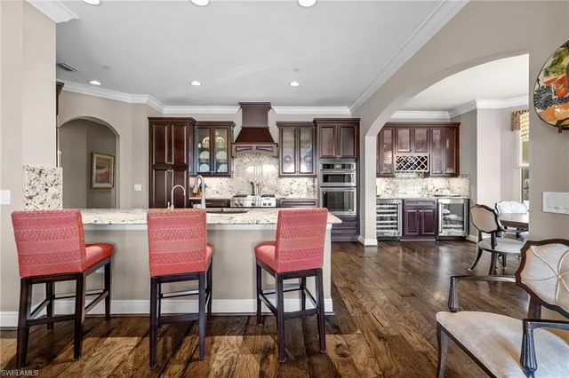 a kitchen with stainless steel appliances kitchen island granite countertop a dining table chairs stove a refrigerator and kitchen view