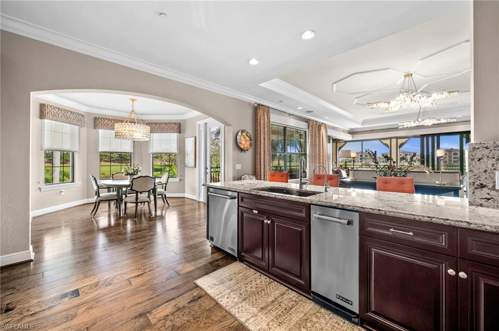 16436 Carrara Way, Unit 102 Naples, FL 34110 - Photo 12 of 43 Kitchen featuring a chandelier, light stone counters, healthy amount of natural light, crown molding, and recessed lighting
