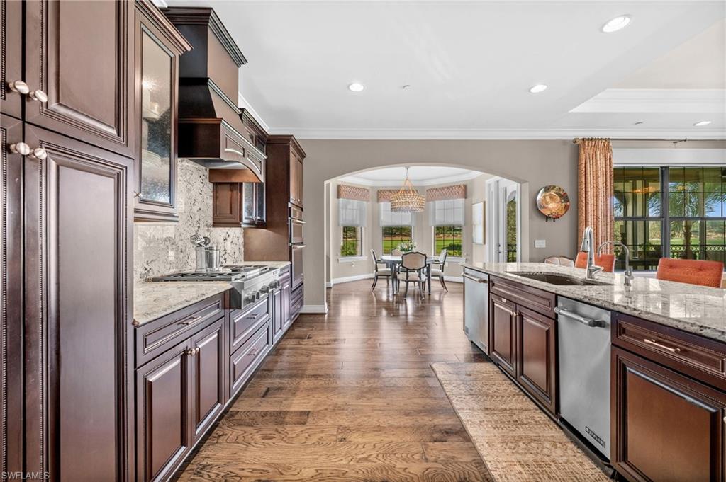 16436 Carrara Way, Unit 102 Naples, FL 34110 - Photo 13 of 43 Kitchen featuring dark brown cabinetry, light stone countertops, tasteful backsplash, pendant lighting, and stainless steel appliances
