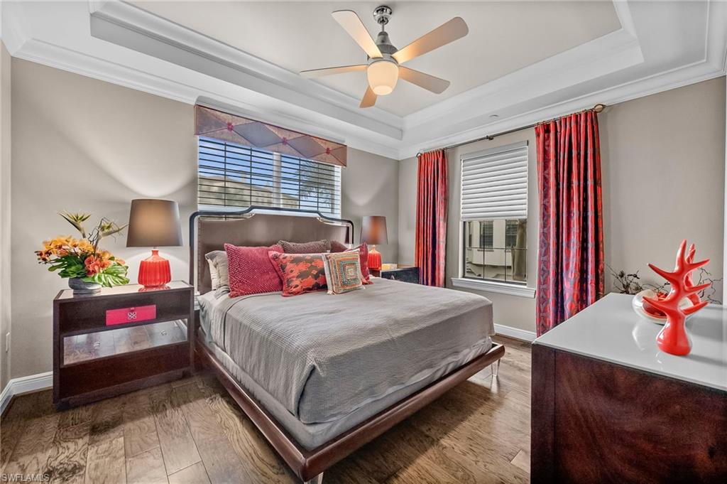 16436 Carrara Way, Unit 102 Naples, FL 34110 - Photo 27 of 43 Bedroom with crown molding, a raised ceiling, hardwood / wood-style flooring, multiple windows, and a ceiling fan