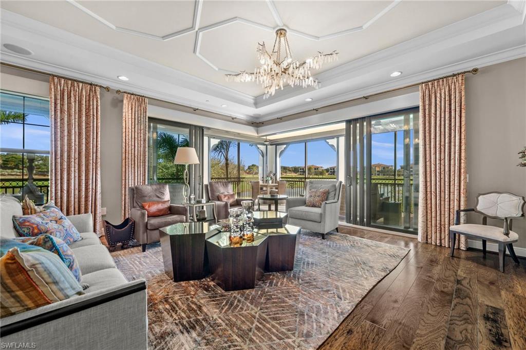 16436 Carrara Way, Unit 102 Naples, FL 34110 - Photo 7 of 43 Living area featuring dark wood-style flooring, a chandelier, crown molding, a tray ceiling, and recessed lighting