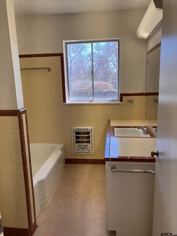 a bathroom with a tub a sink and a large window