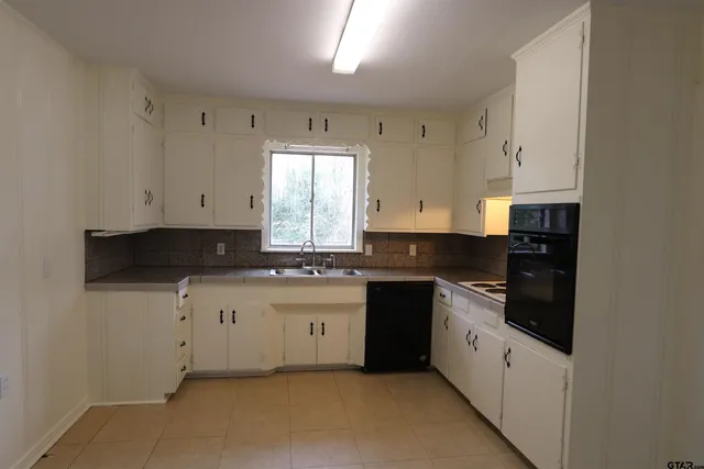 a kitchen with granite countertop white cabinets sink and stainless steel appliances