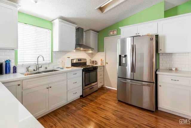 a kitchen with stainless steel appliances a refrigerator sink and white cabinets