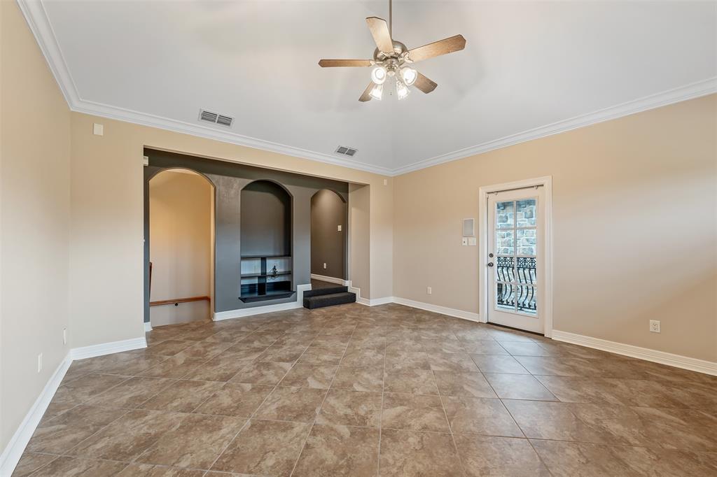 20389 County Road 178 Flint, TX 75762 - Photo 30 of 40 Spacious room featuring tile flooring, crown molding, a ceiling fan with integrated lighting, and a built-in entertainment niche with arched shelving