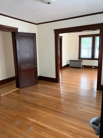 a view of empty room with wooden floor and fan