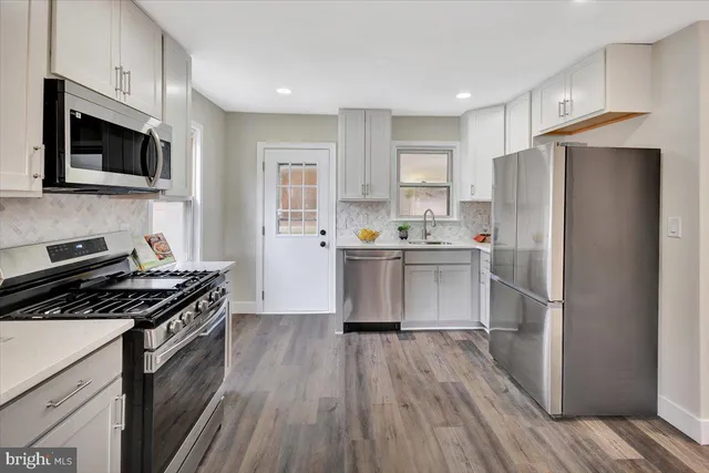 a kitchen with stainless steel appliances a refrigerator a stove top oven a sink and cabinets