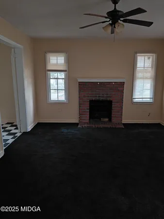 a living room with a black ceiling fan and a fireplace