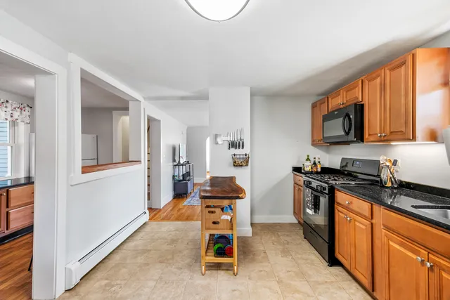 a kitchen with stainless steel appliances granite countertop a stove top oven a sink dishwasher a dining table and chairs with wooden floor