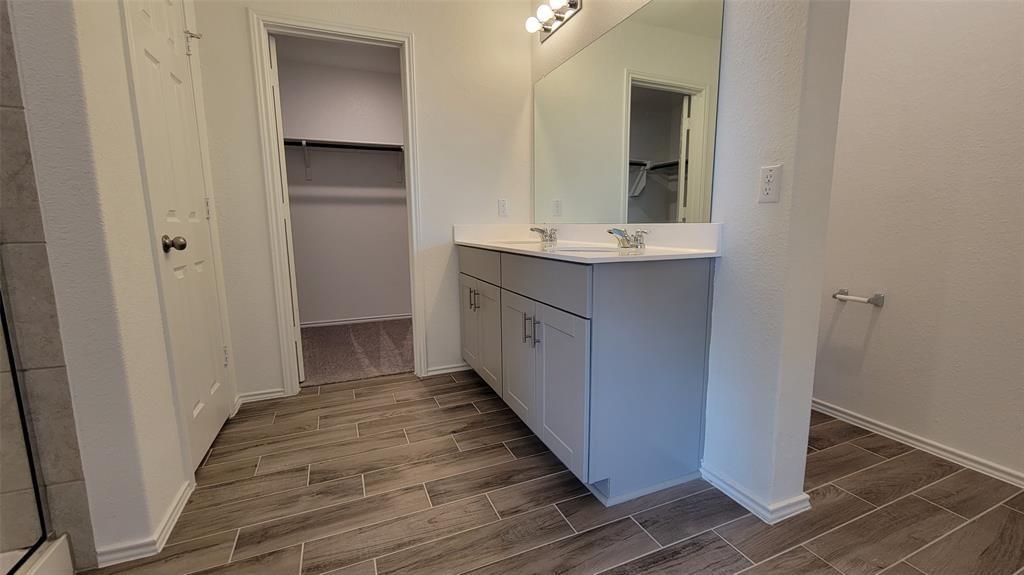452 Pickrell Loop Georgetown, TX 78628 - Photo 14 of 19 Full bath featuring wood finish floors, double vanity, a spacious closet, and a textured wall