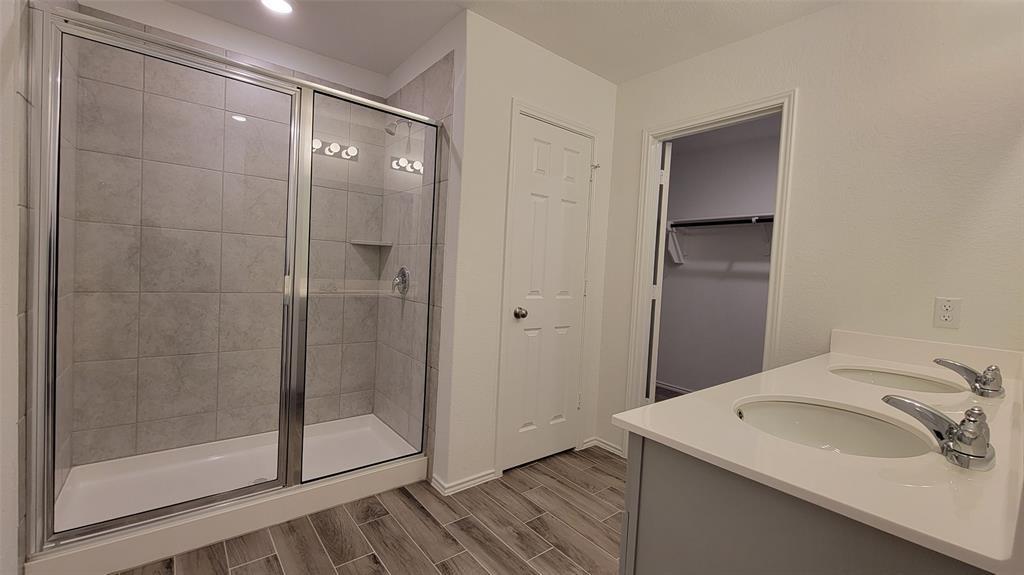 452 Pickrell Loop Georgetown, TX 78628 - Photo 15 of 19 Bathroom featuring double vanity, wood tiled floors, and a stall shower