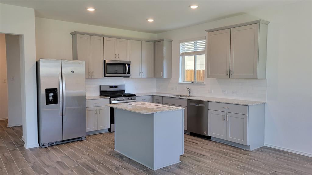 452 Pickrell Loop Georgetown, TX 78628 - Photo 3 of 19 Kitchen with stainless steel appliances, decorative backsplash, wood tiled floors, light stone counters, and recessed lighting
