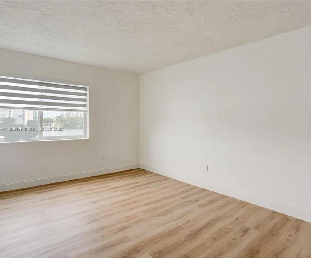 5501 Northwest 7th Street, Unit E408 Miami, FL 33126 - Photo 20 of 27 a view of an empty room with wooden floor and a window