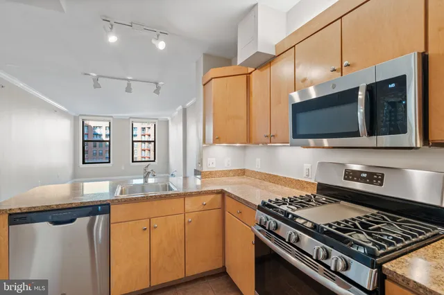 a kitchen with stainless steel appliances granite countertop white cabinets and a stove top oven