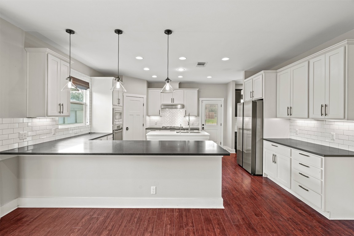 1912 South Church Street Georgetown, TX 78626 - Photo 8 of 40 a large kitchen with stainless steel appliances kitchen island a large counter top a sink a refrigerator and a wooden floor