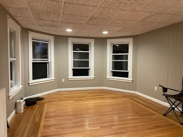 a view of an empty room with a window and wooden floor