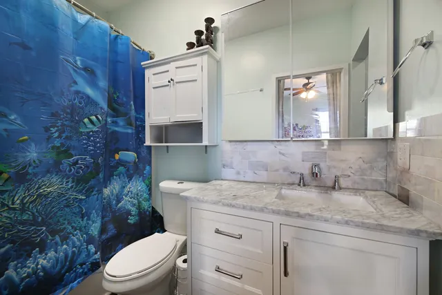 a bathroom with a granite countertop toilet sink and mirror