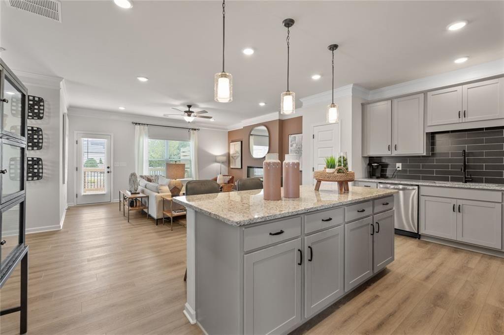 310 Caroline Place, Unit 100 Villa Rica, GA 30180 - Photo 12 of 30 a kitchen with kitchen island granite countertop a stove a sink a center island and couches with wooden floor