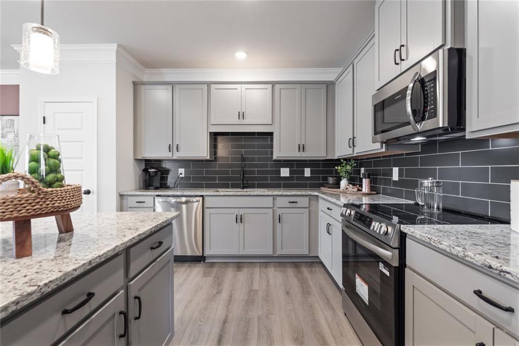 310 Caroline Place, Unit 100 Villa Rica, GA 30180 - Photo 14 of 30 a kitchen with stainless steel appliances granite countertop a stove top oven a sink dishwasher and a microwave oven with white cabinets