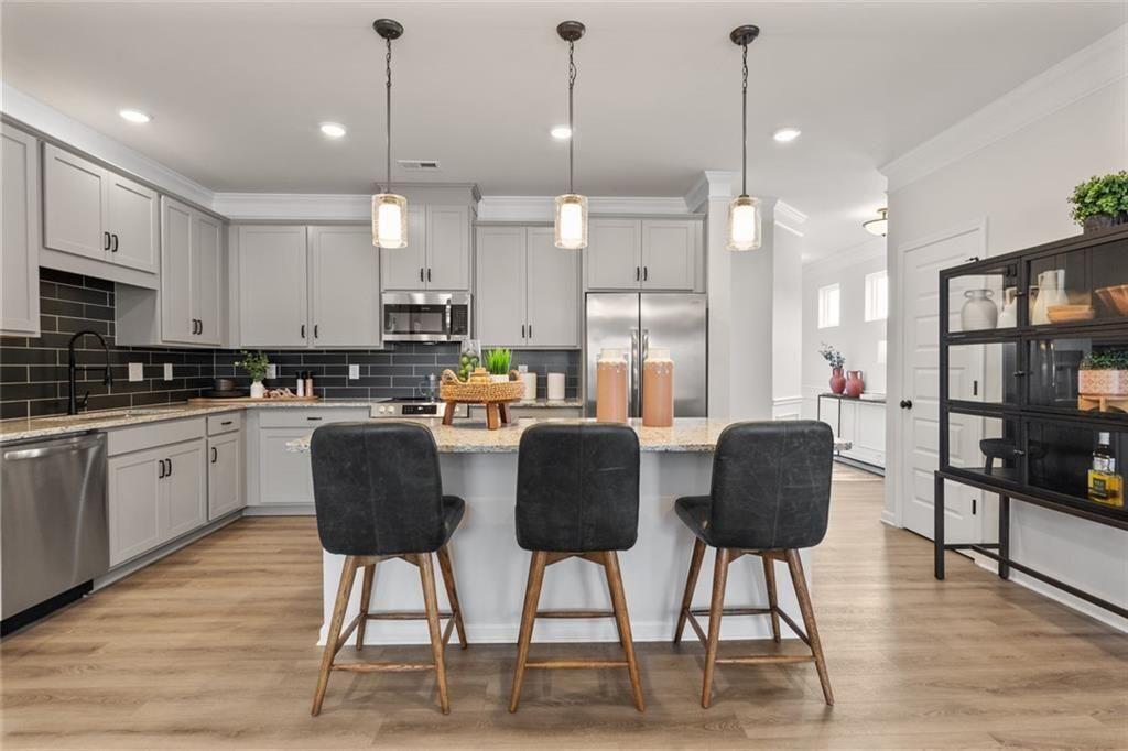 310 Caroline Place, Unit 100 Villa Rica, GA 30180 - Photo 9 of 30 a kitchen with stainless steel appliances granite countertop a refrigerator a stove a sink dishwasher a dining table and chairs with wooden floor