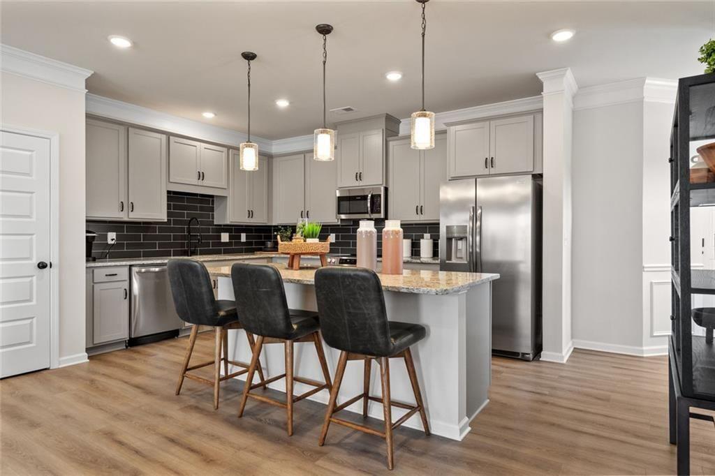 310 Caroline Place, Unit 100 Villa Rica, GA 30180 - Photo 10 of 30 a kitchen with stainless steel appliances kitchen island granite countertop a refrigerator a stove a sink dishwasher and a dining table with wooden floor