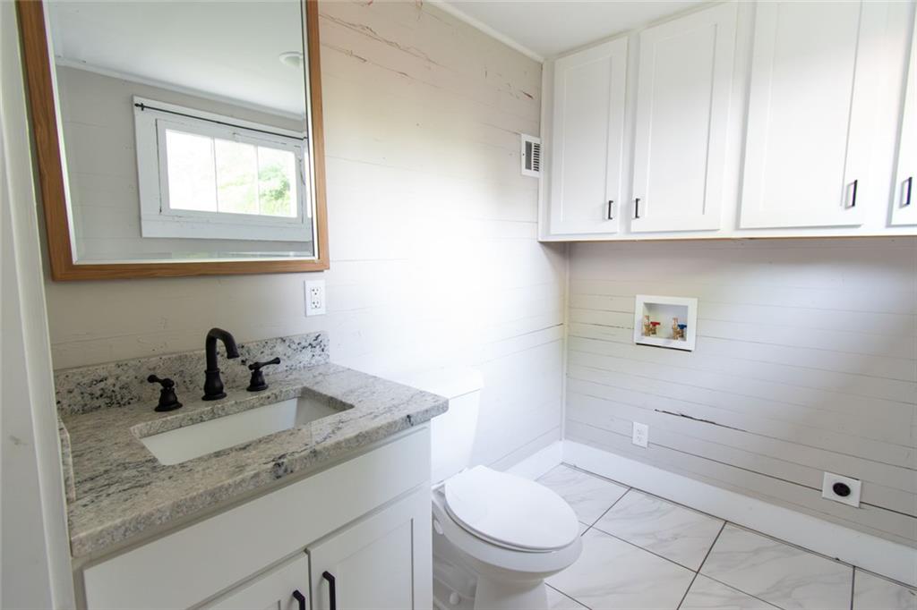 702 Radford Street Monroe, GA 30655 - Photo 41 of 49 a bathroom with a granite countertop sink toilet and mirror