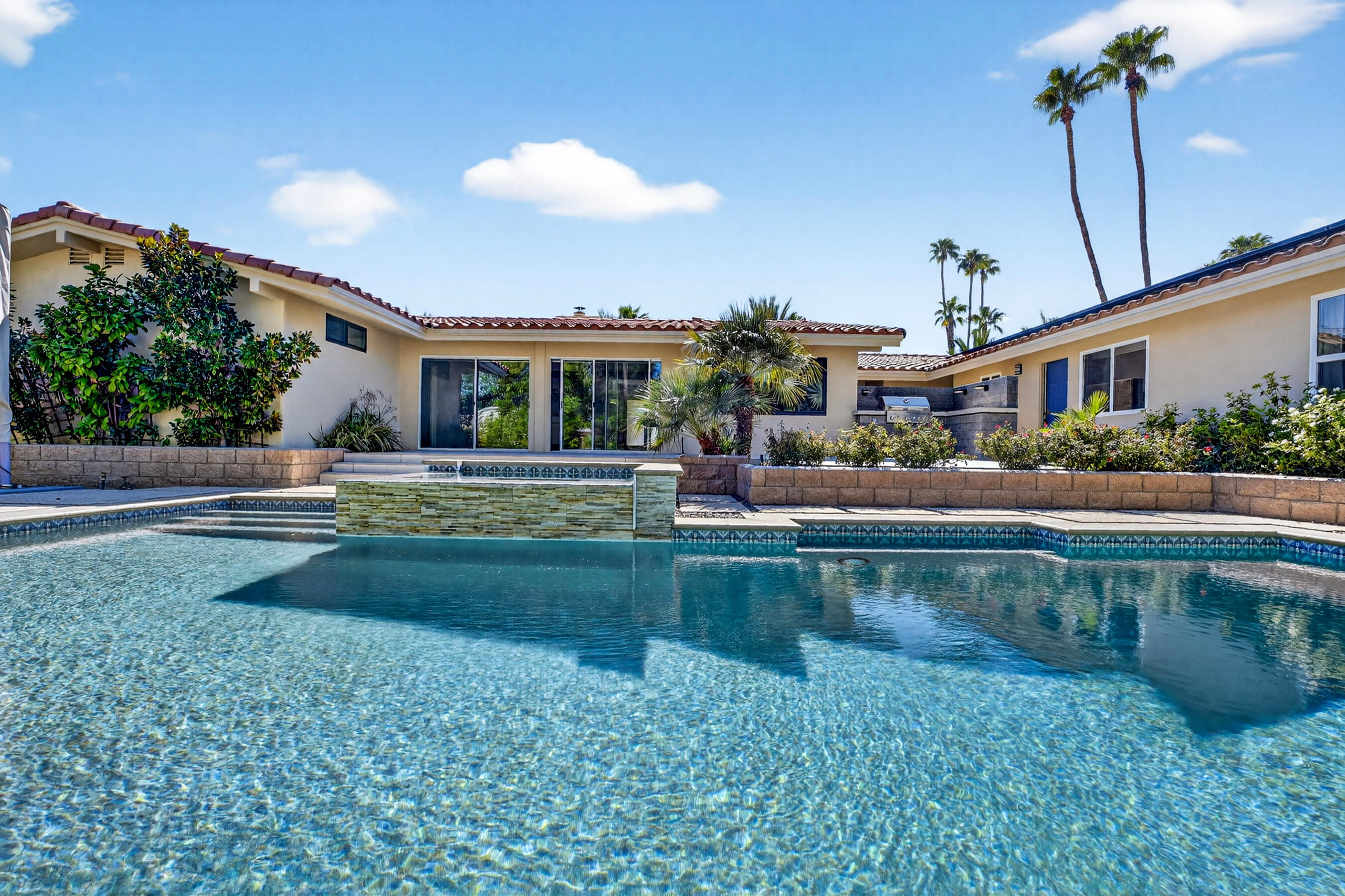 74090 Setting Sun Trail Palm Desert, CA 92260 - Photo 30 of 46 a front view of a house with garden and swimming pool