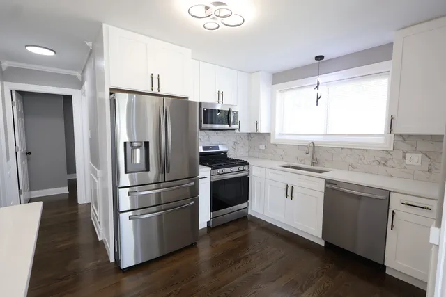 a kitchen with stainless steel appliances white cabinets and wooden floor