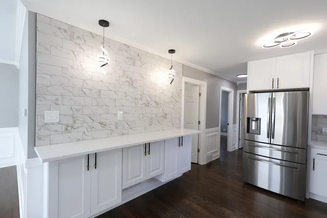 a kitchen with stainless steel appliances a refrigerator and white cabinets