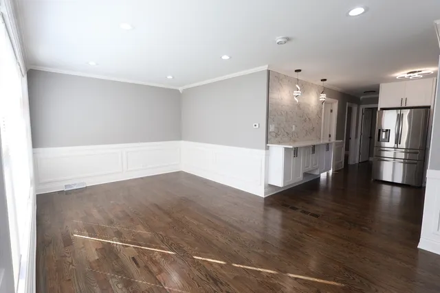 a view of a kitchen with a refrigerator and wooden floor