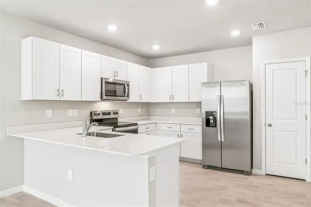 a kitchen with stainless steel appliances granite countertop a stove top oven a sink and dishwasher a refrigerator with wooden floor