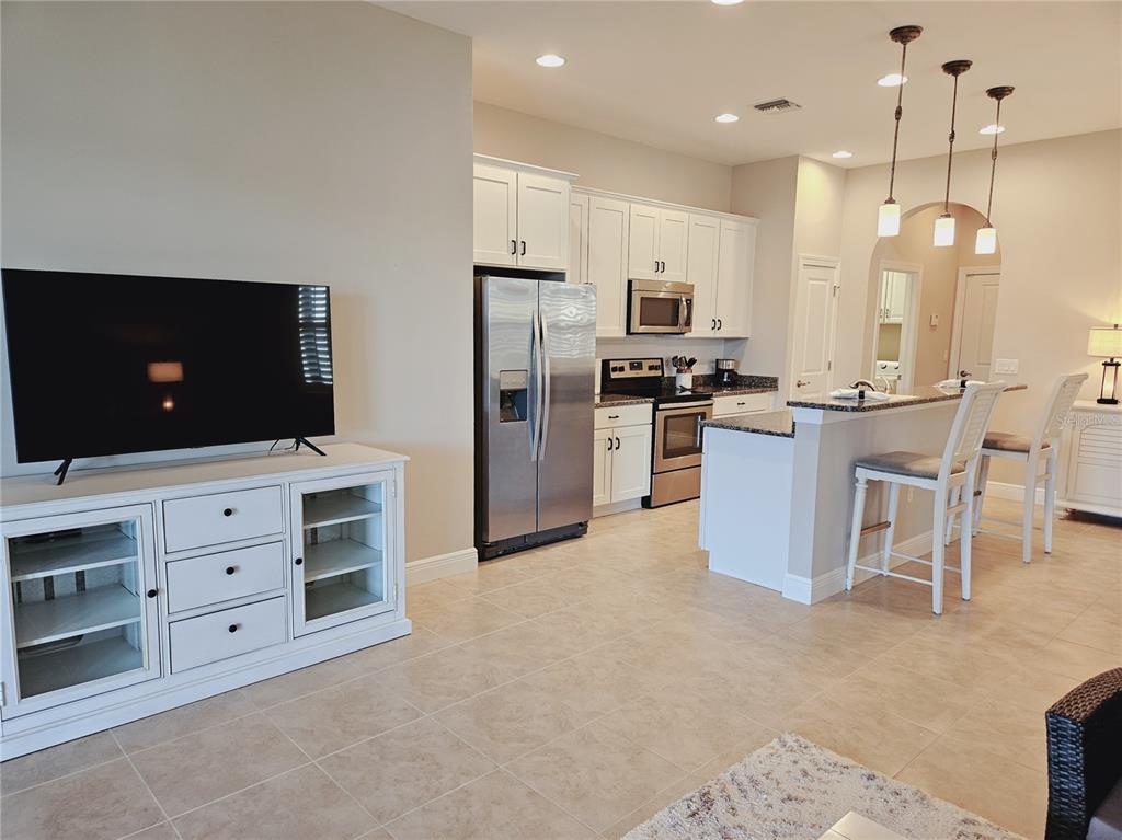 10468 Crooked Creek Drive Venice, FL 34293 - Photo 17 of 44 a kitchen with stainless steel appliances kitchen island granite countertop a stove top oven a refrigerator and cabinets