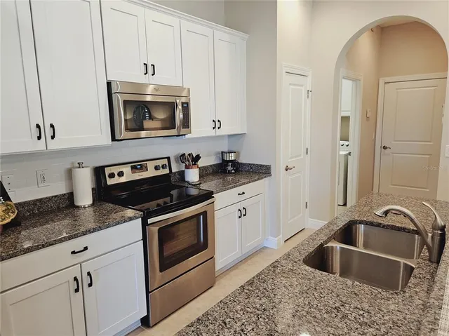 a kitchen with granite countertop white cabinets and stainless steel appliances