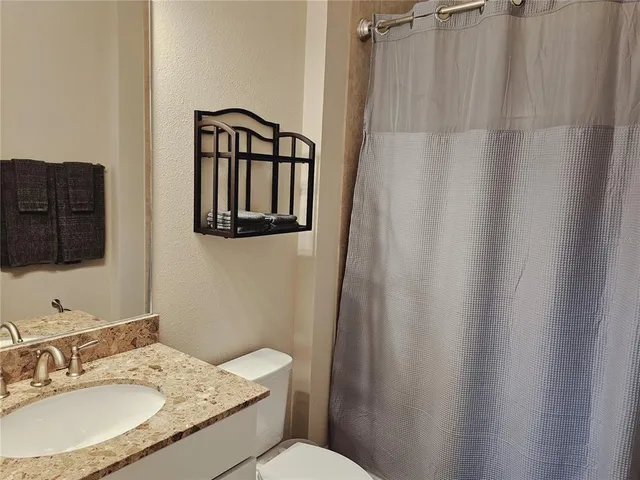 a bathroom with a granite countertop sink toilet and mirror