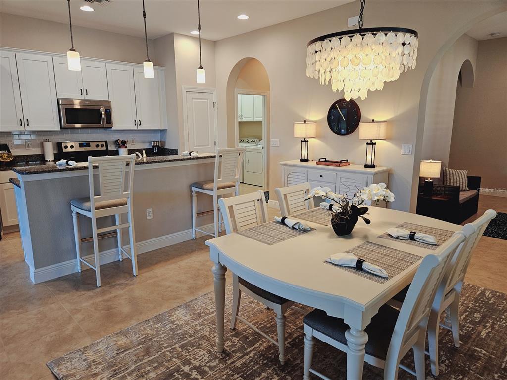 10468 Crooked Creek Drive Venice, FL 34293 - Photo 6 of 44 a kitchen with stainless steel appliances kitchen island granite countertop a table chairs and a refrigerator